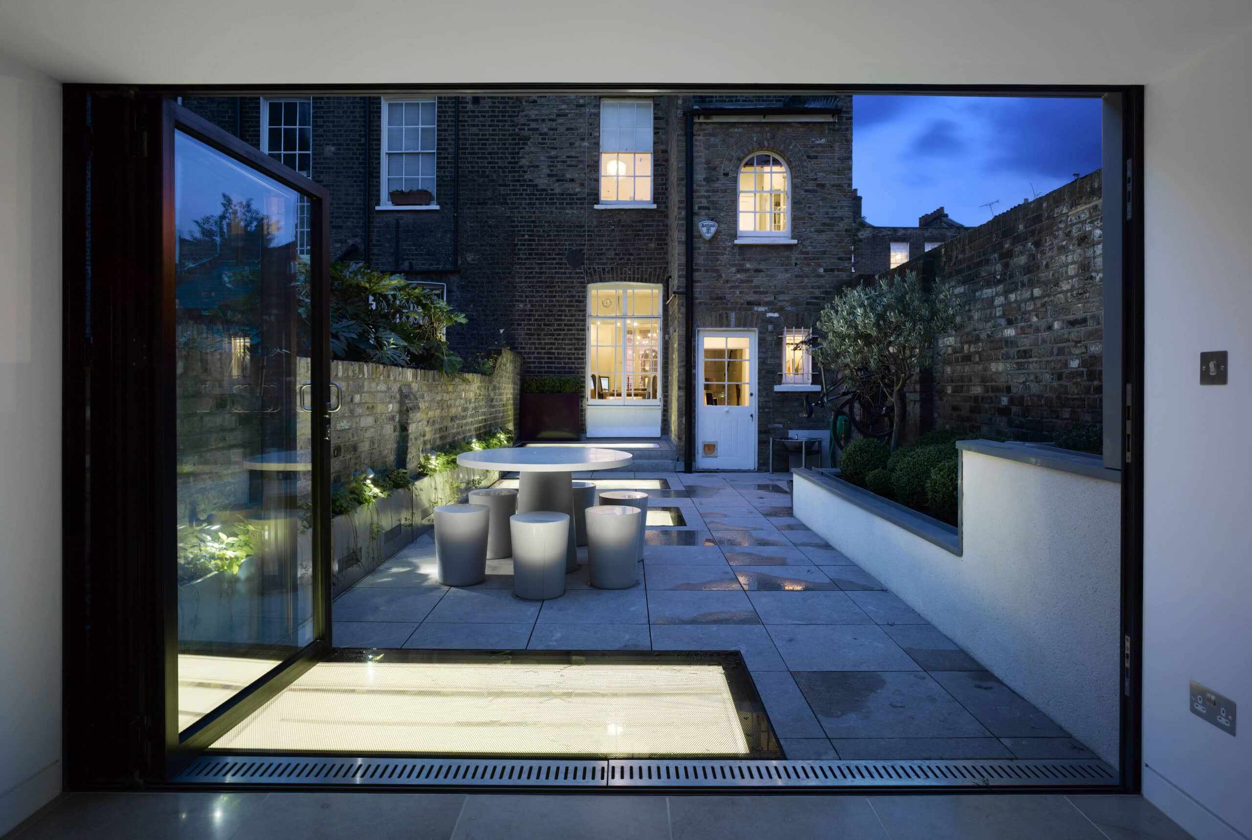 Interior opening towards the illuminated garden at night.