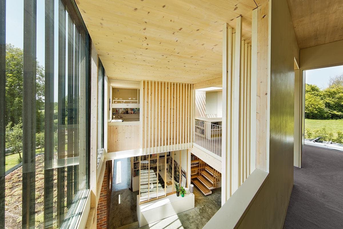 Contemporary wooden atrium flooded with natural light and lush greenery views.