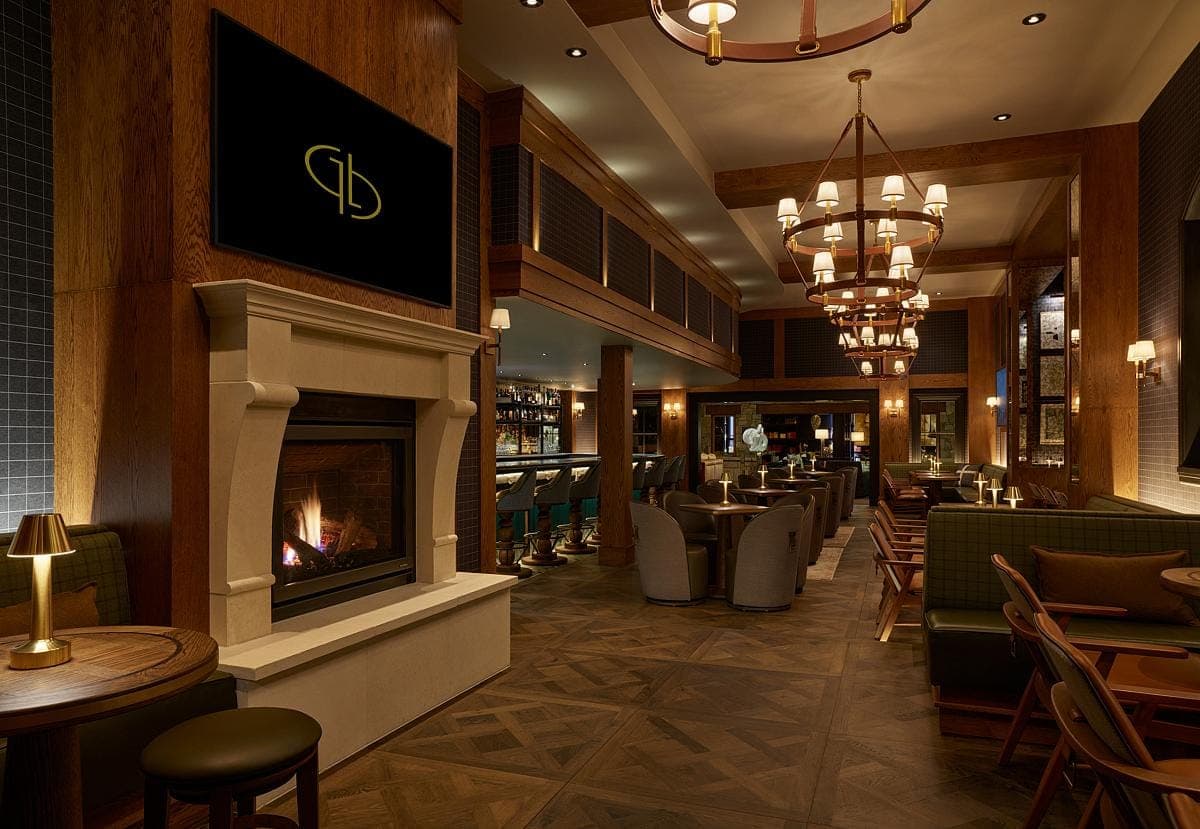 Luxurious bar and lounge with fireplace, elegant chandeliers, and dark wood furnishings.