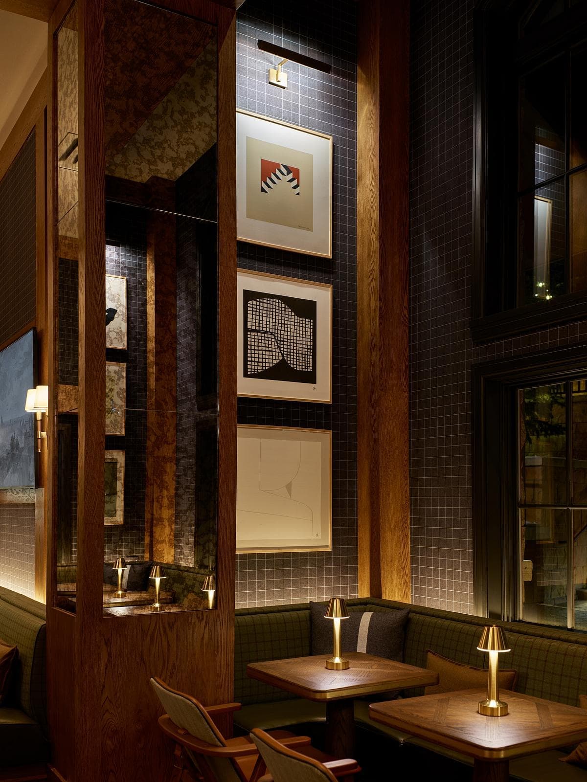 Modern restaurant with elegant lighting, cushioned seating, abstract art, and large windows.