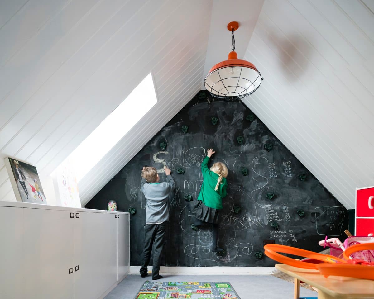 Attic playroom with chalkboard wall, natural light, and storage cabinets for creative and educational activities.