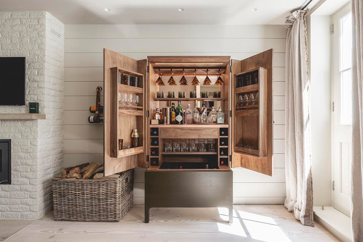 Stylish bar cabinet with natural wood finish, showcasing spirits and glassware in a modern rustic space.