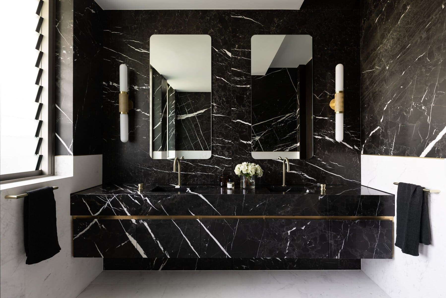 Luxurious black marble bathroom with gold accents and modern fixtures.
