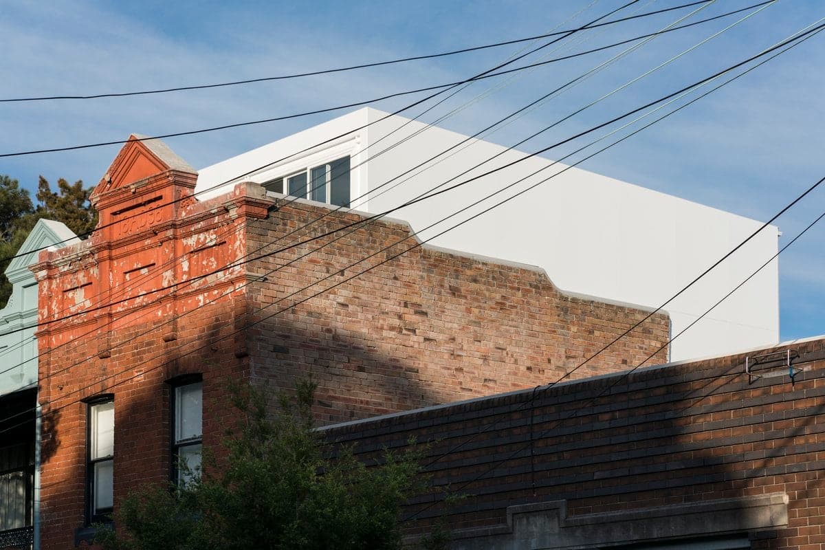 Urban cityscape featuring historic brick building and modern white structure with utility lines overhead.