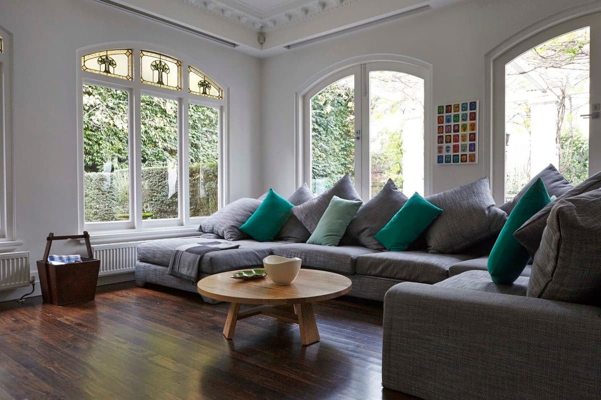 Cozy living room with gray sofa, arched windows, and colorful wall art.