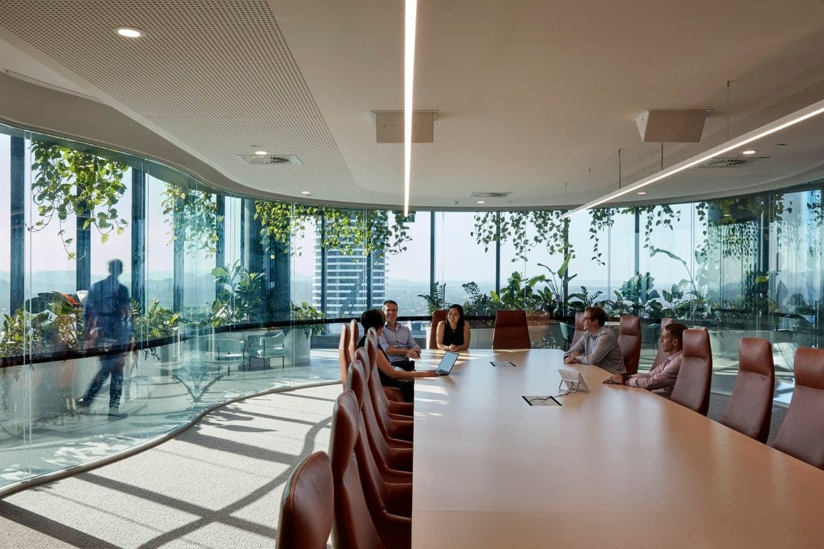 Modern conference room with city view, natural light, and greenery.