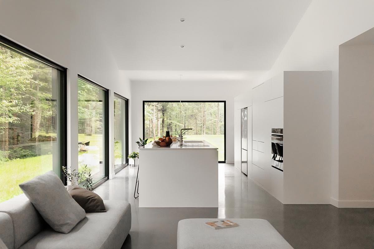 Stylish modern living room with large windows and nature views, embodying minimalist design.