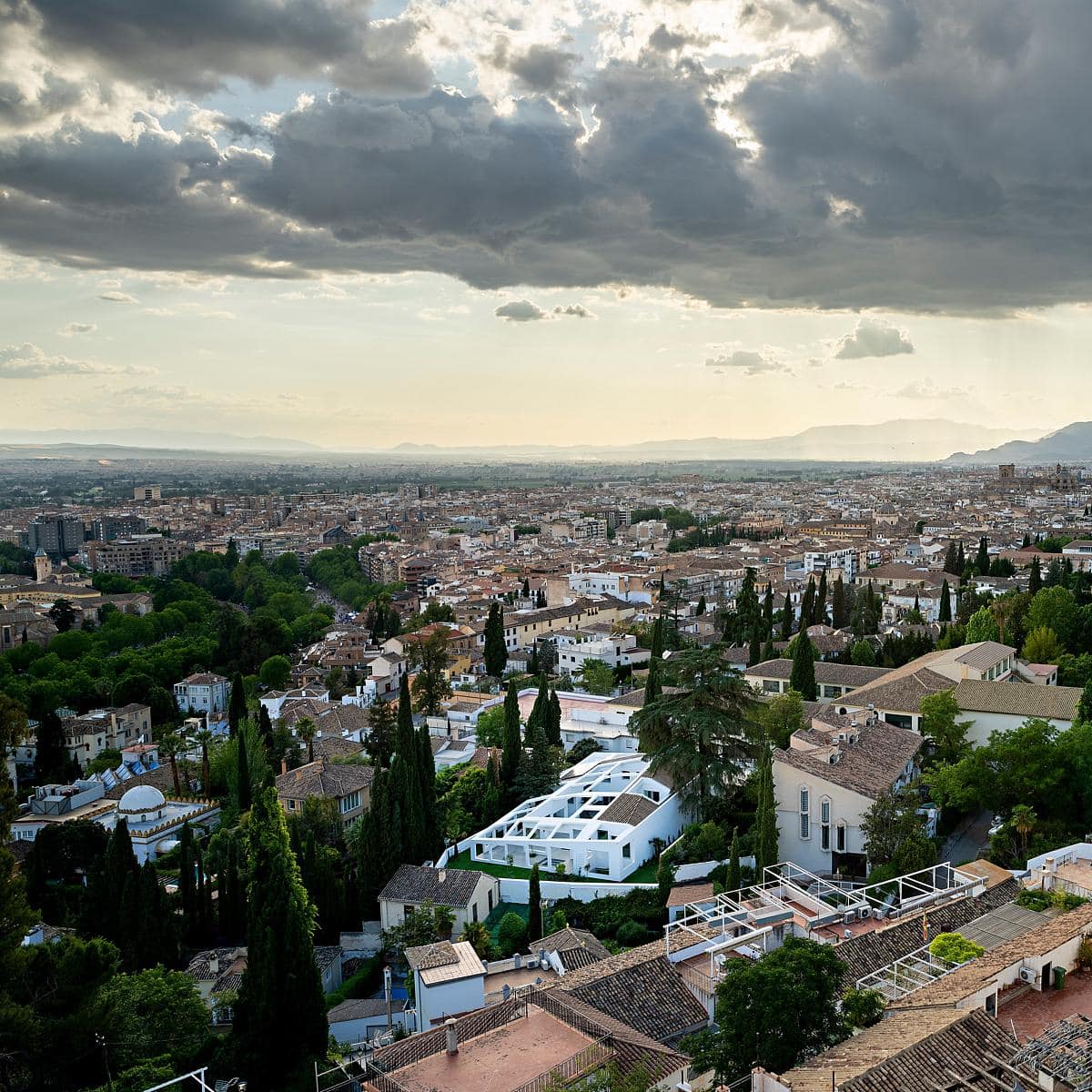 Mediterranean cityscape blending greenery with charming architecture under a dramatic sky.