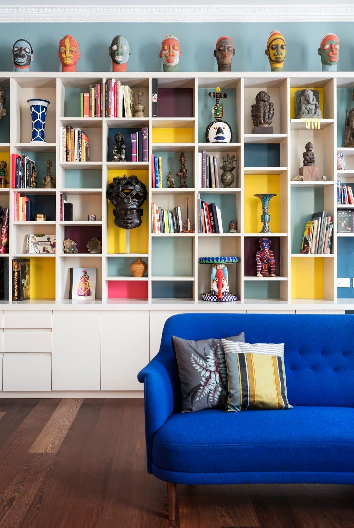 Eclectic living room with vibrant shelving and blue sofa featuring diverse decor elements.