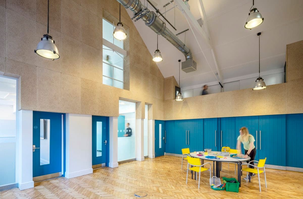 School interior with high ceilings, blue accents and round tables.