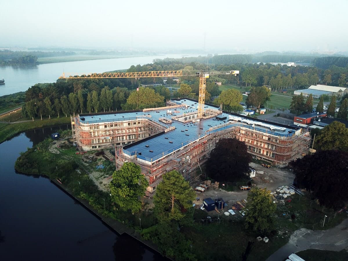 Aerial view of a waterfront healthcare clinic under construction amidst lush greenery.