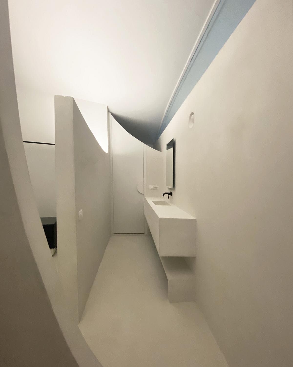 Stylish minimalist bathroom featuring a unique curved wall design and bright, airy colours.