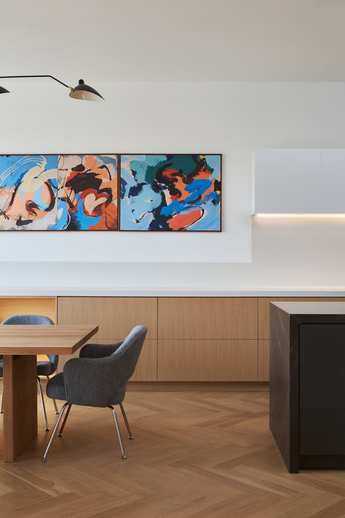 Modern dining area with abstract triptych art and minimalist furnishings in a Toronto residence.