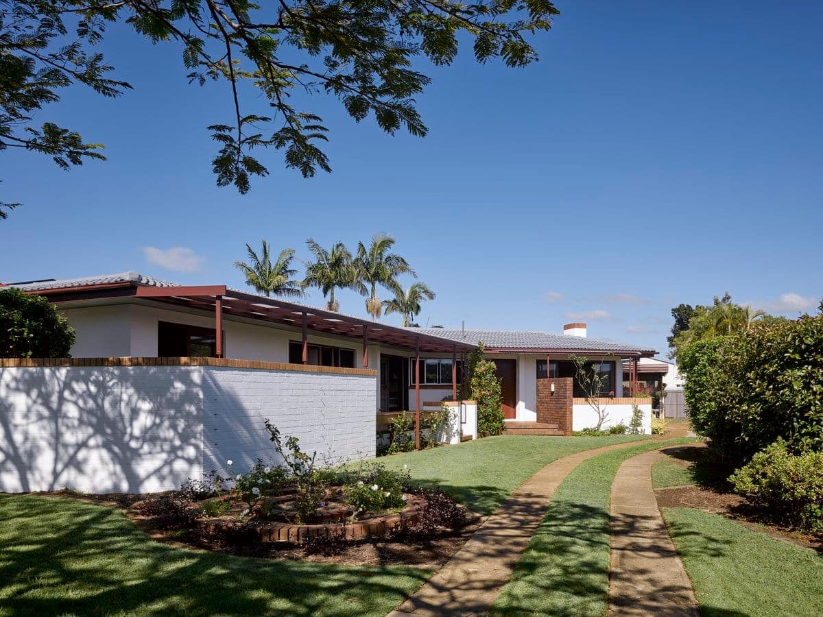 Modern single-story house with lush landscaping and flat roof.
