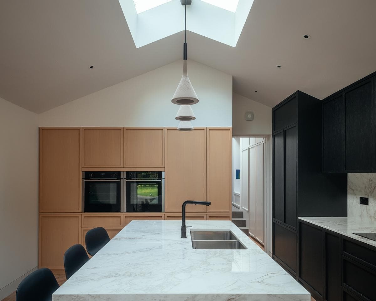 Elegant contemporary kitchen featuring marble island and warm wooden cabinetry, designed by Neil Dusheiko.