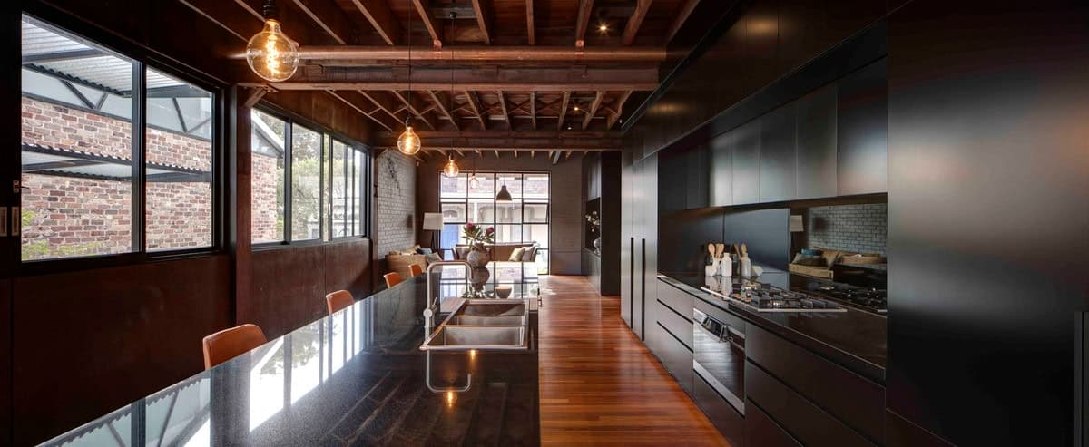 Sleek minimalist kitchen with dark cabinetry, stone island, and abundant natural light.