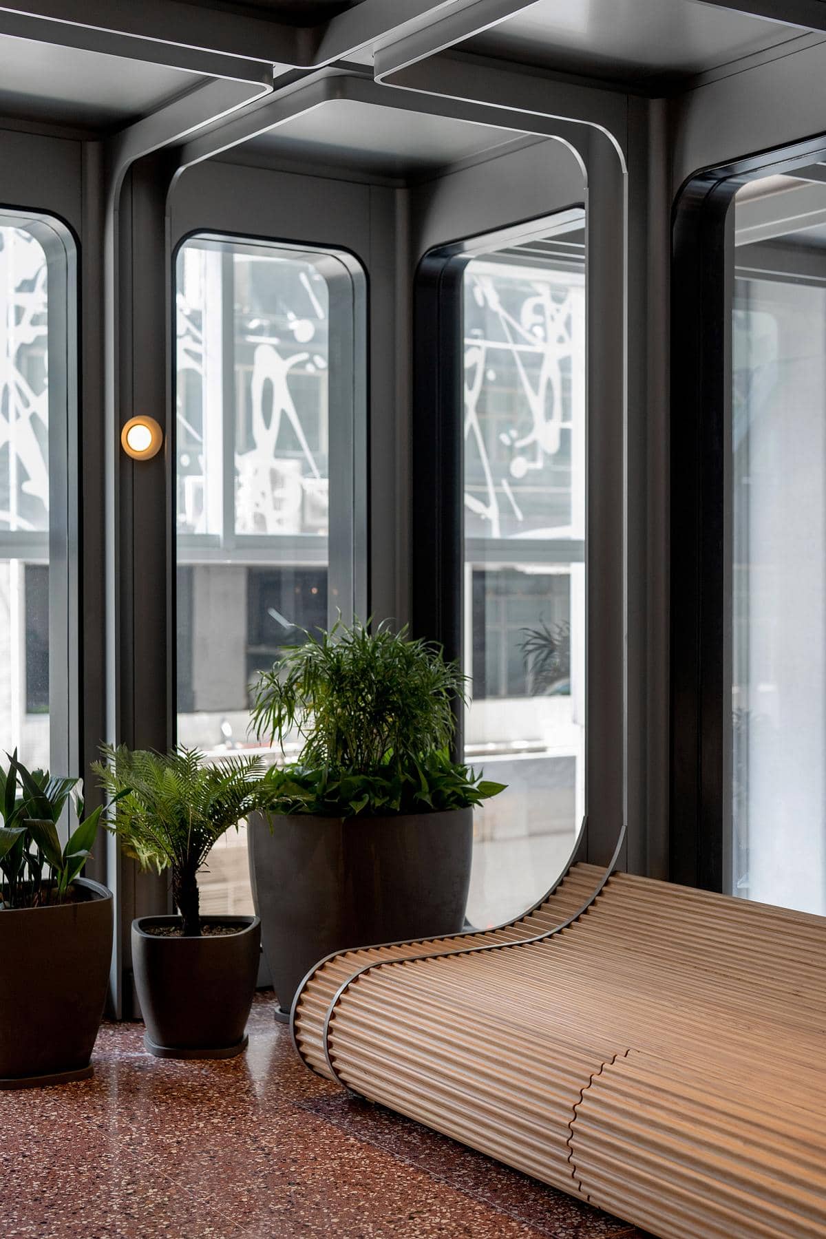 Contemporary lounge with natural light, curved wooden bench, and vibrant indoor plants for comfort.