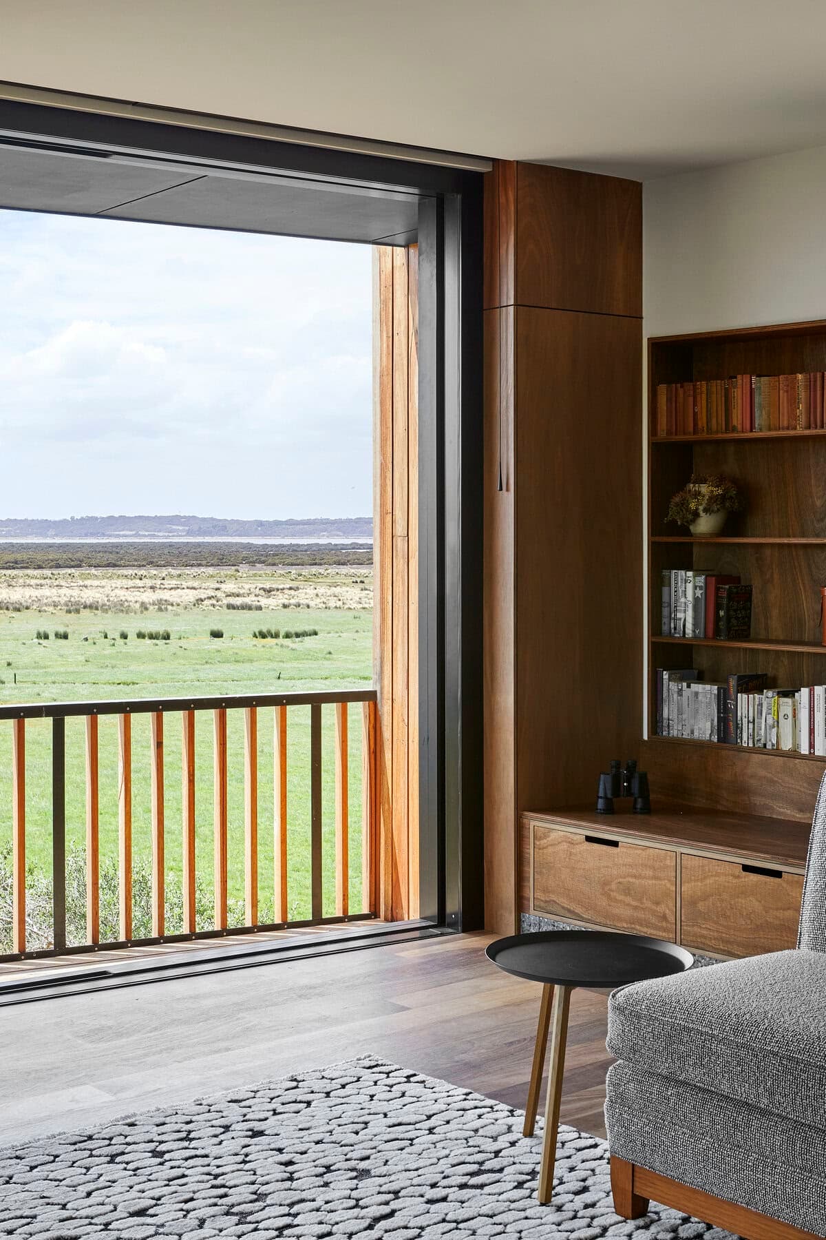Modern living room with cozy chair and stunning nature views through sliding glass door.