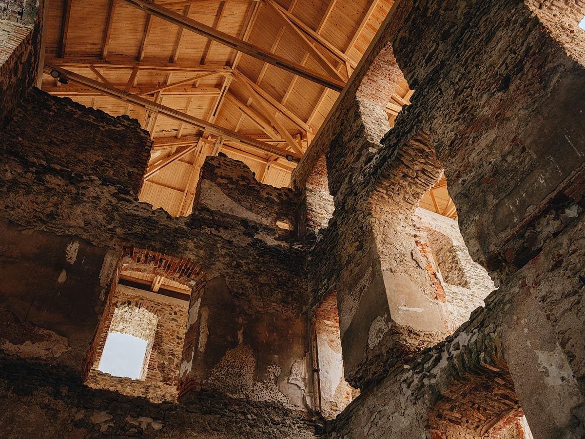 Interior view of historic masonry walls beneath a timber roof structure.