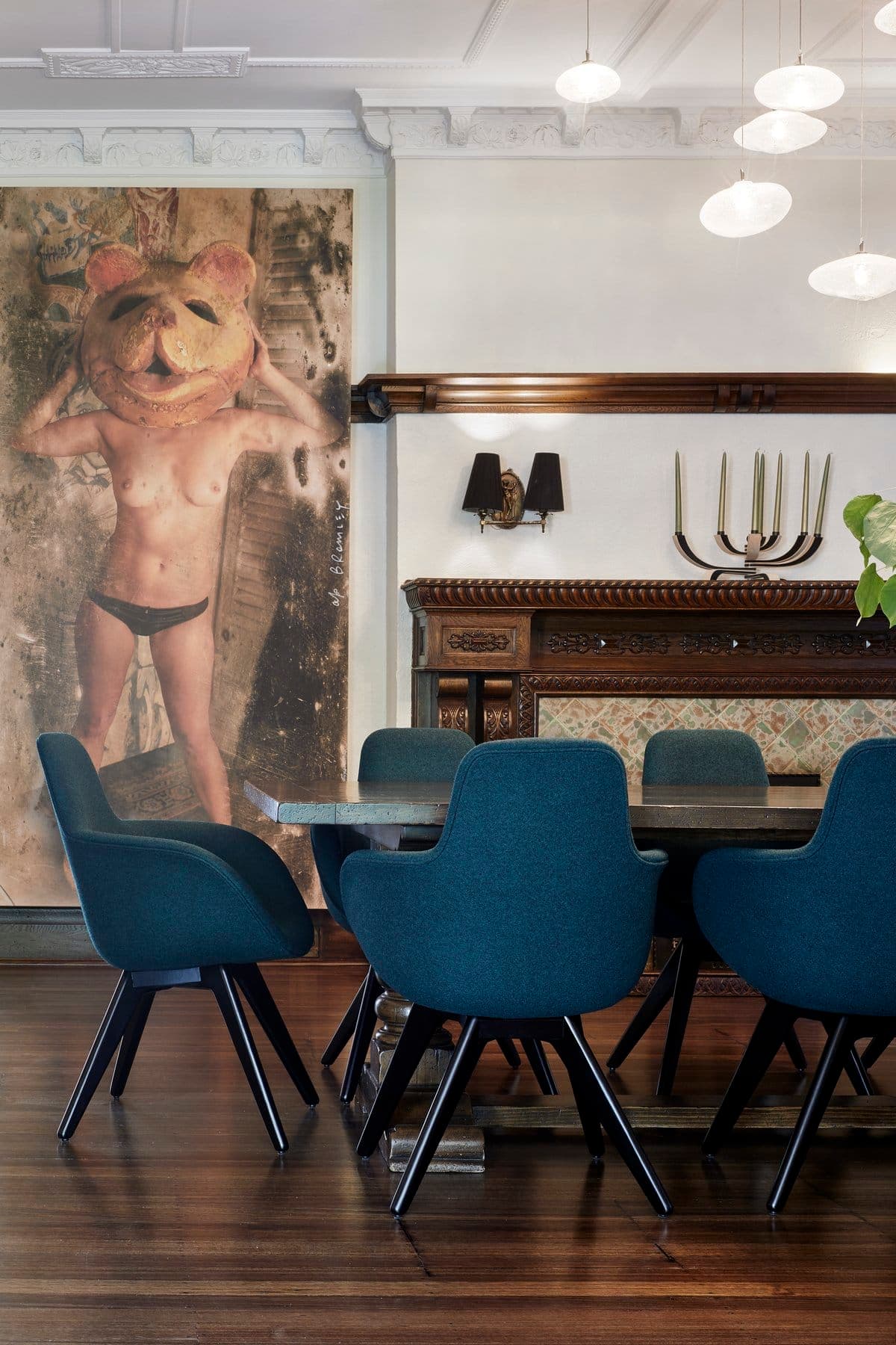 Eclectic dining area with modern art, antique mantelpiece, and contemporary furnishings.