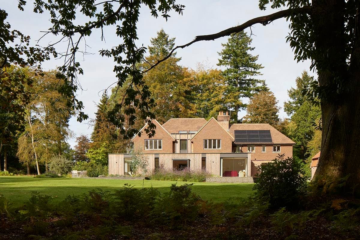 Eco-friendly modern home nestled in lush landscape with solar panels and natural light.