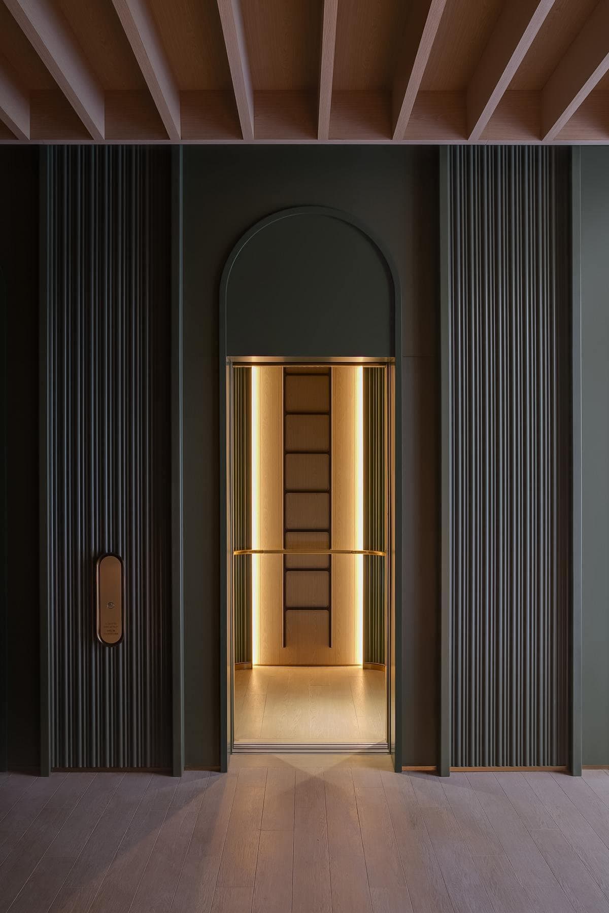 Elegant archway doorway with warm lighting against rich green walls, enhancing modern interior design.