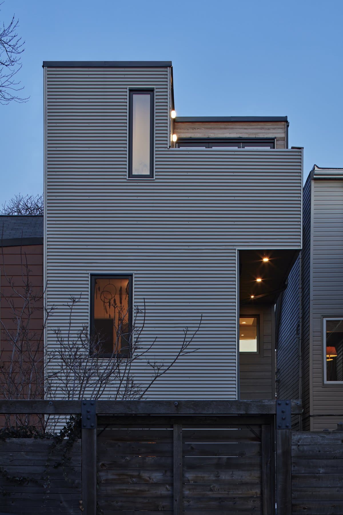 Modern minimalist house with geometric design and industrial facade, featuring cantilevered upper floor.