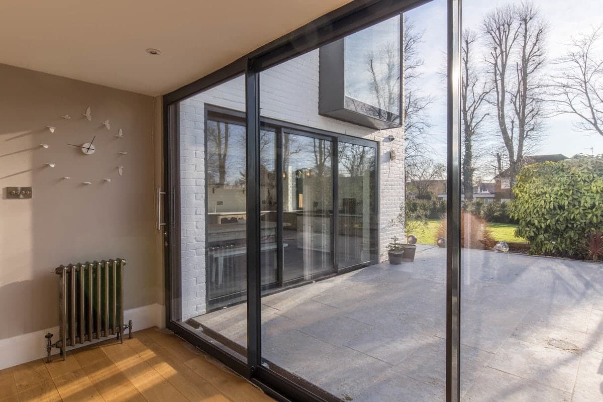 Modern room with glass door opening to patio and garden. Bright, airy, and minimalist design.