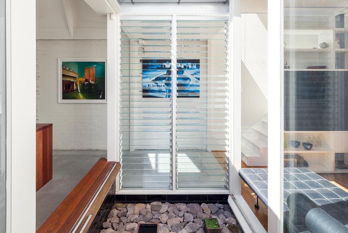 Stylish modern minimalist living space with glass enclosure and artistic decor elements.