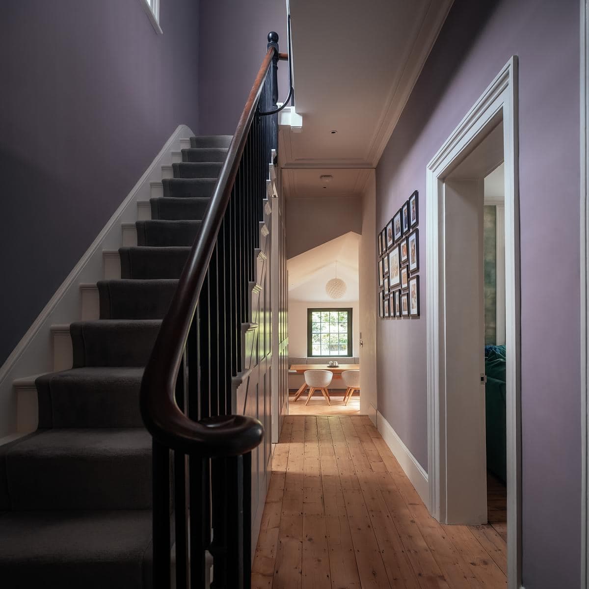 Cozy modern hallway design featuring lavender walls and inviting staircase by Neil Dusheiko Architects.