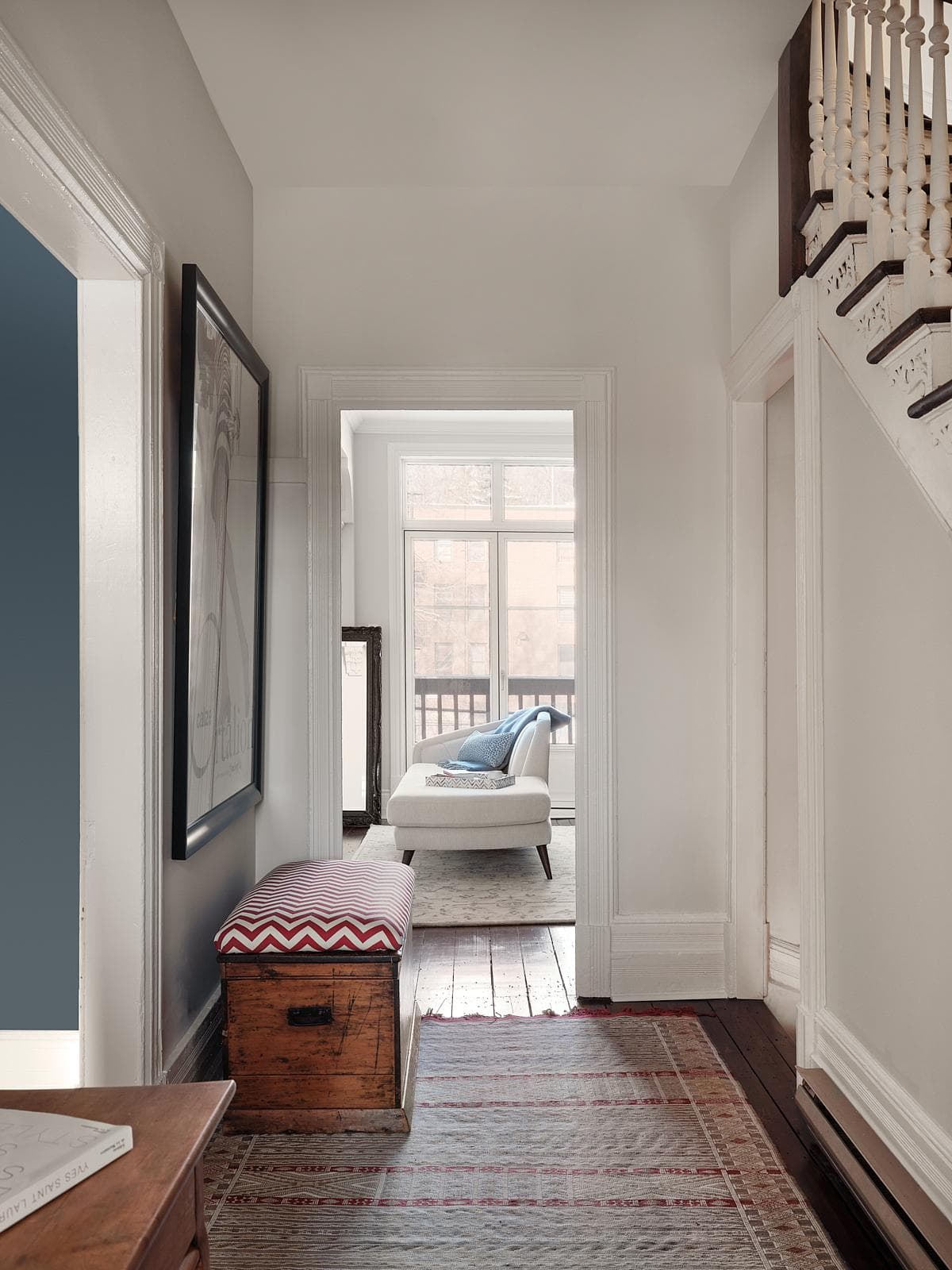 Chic hallway features artwork, vintage bench, and abundant natural light for a welcoming atmosphere.
