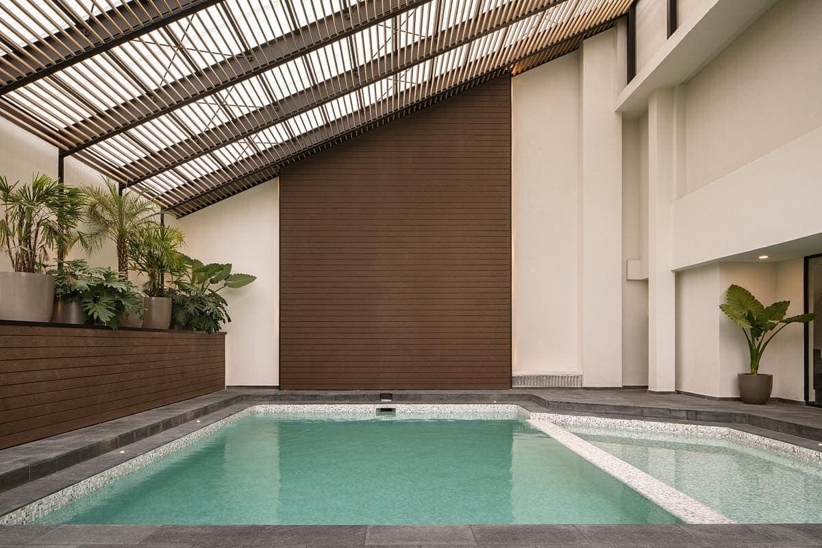 Modern indoor pool area with tranquil design, natural light, and lush greenery.