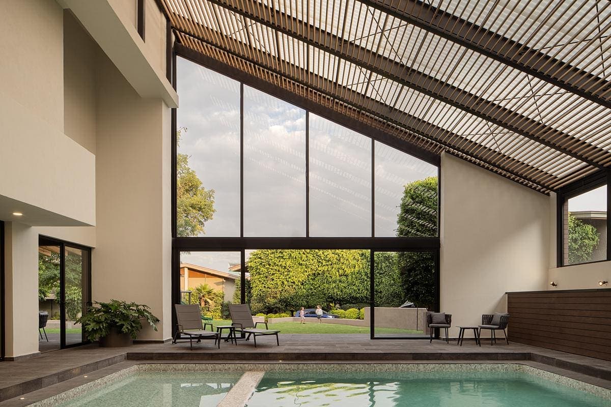 Contemporary indoor pool with natural light and lush garden views for a tranquil retreat.