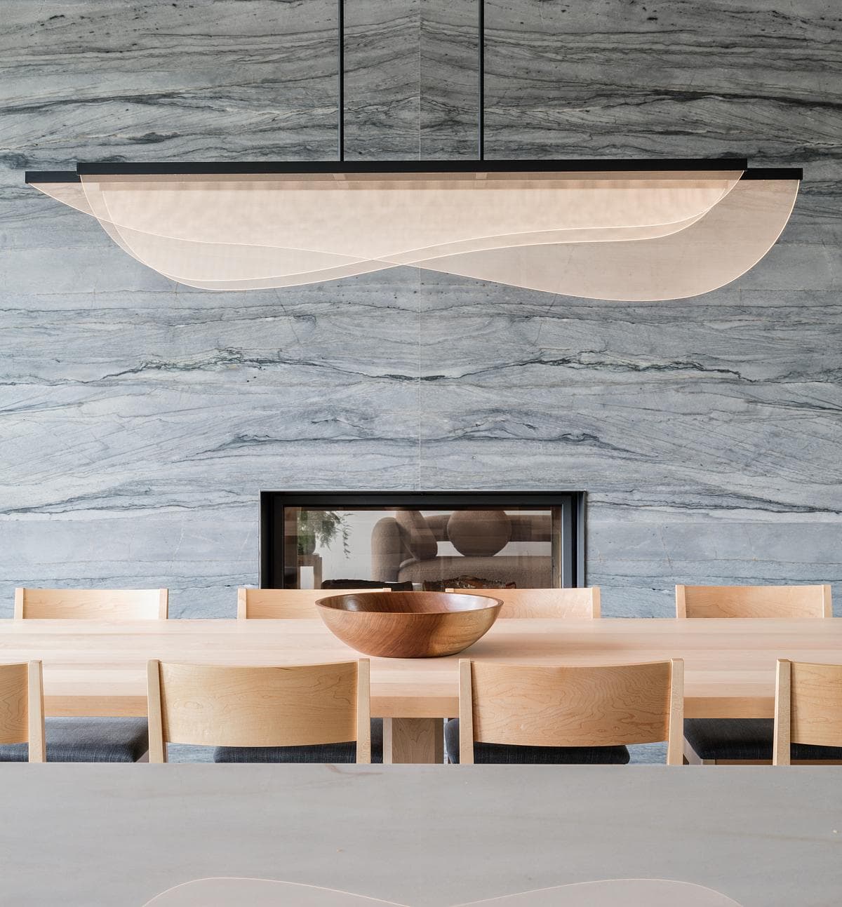 Stylish modern dining room featuring natural materials, cozy fireplace, and elegant lighting.