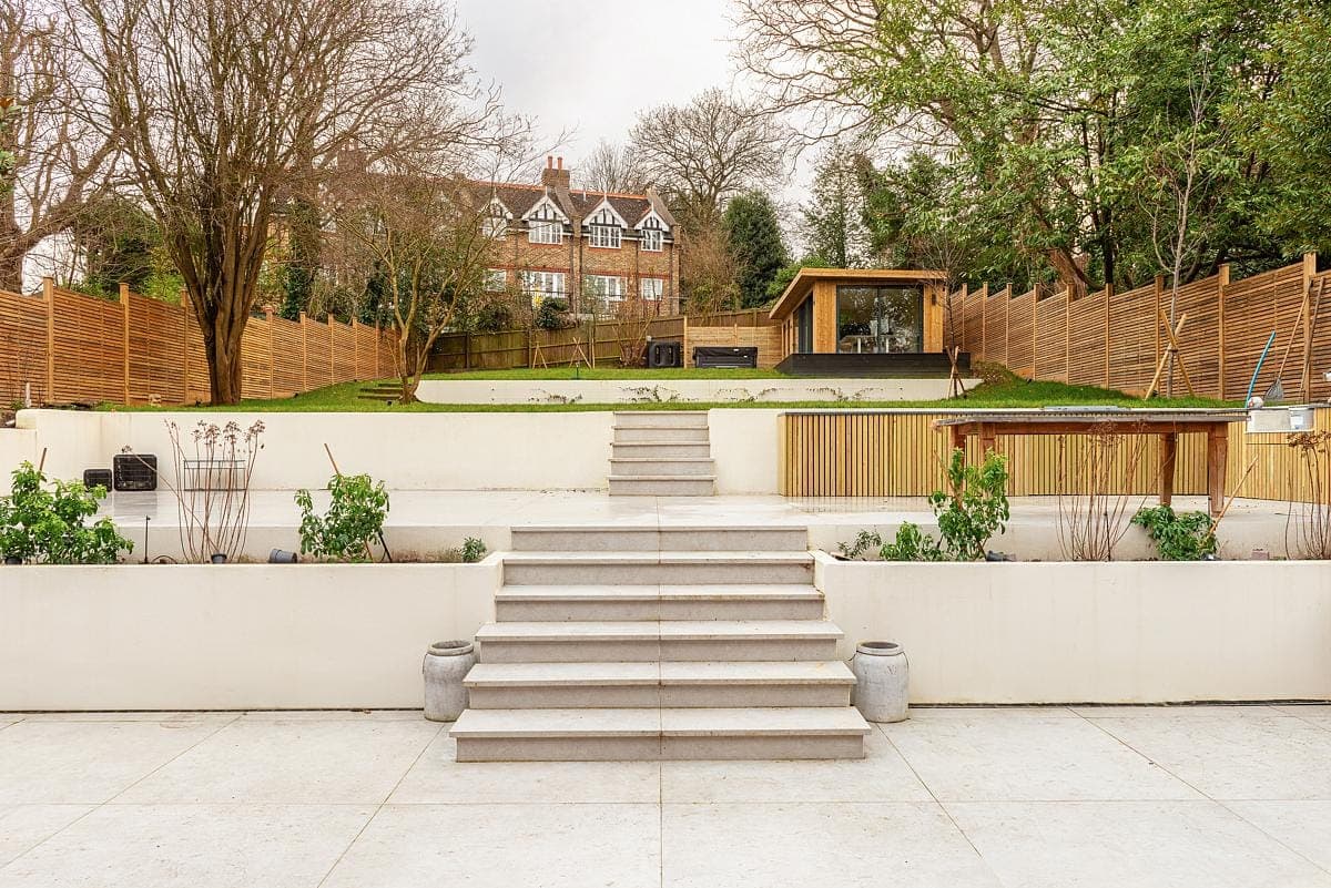 Elegant tiered garden featuring stone steps, lush greenery, and a charming wooden structure.