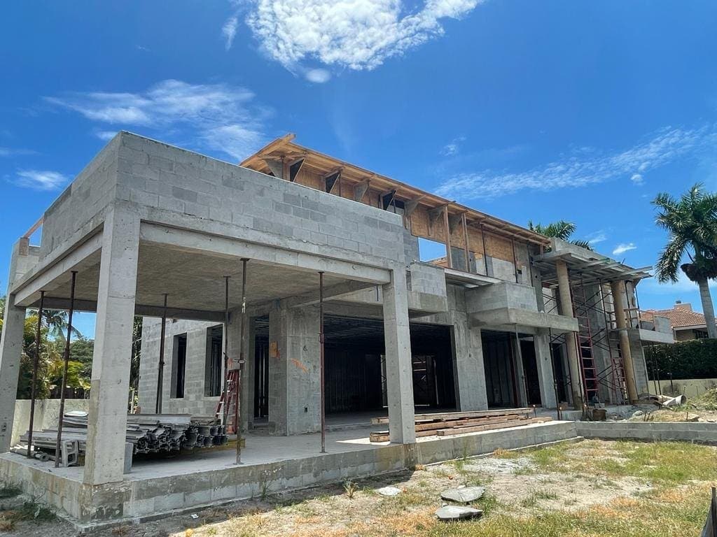 Concrete house structure under construction, with exposed columns and floor slabs.