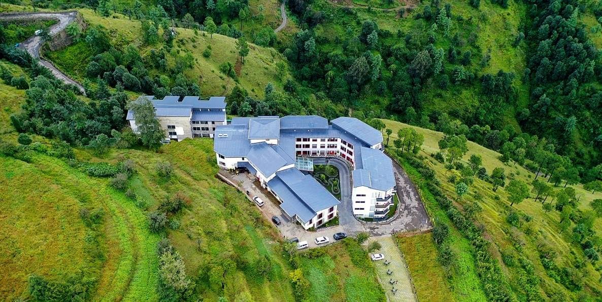Multi-story ITC Welcome Hotel amidst lush hillside greenery with modern design and connected wings.