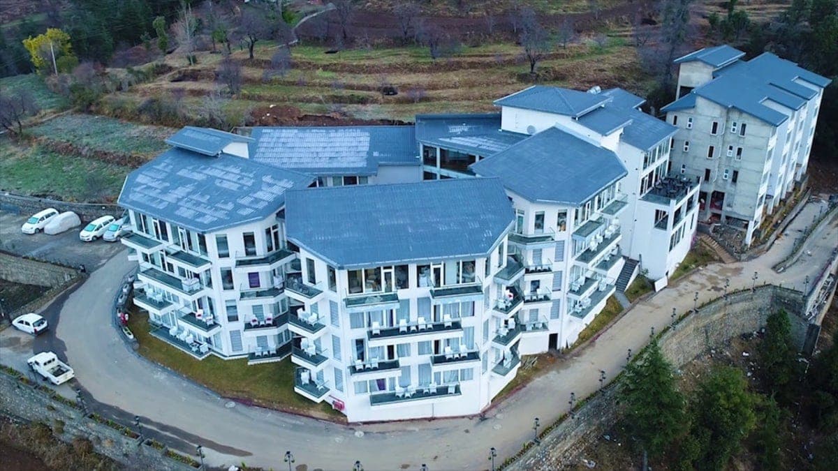 Modern multi-story ITC Welcome Hotel amidst serene semi-rural landscape.