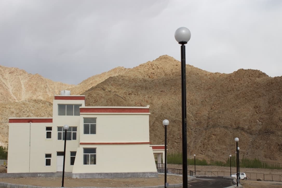 Modern Leh Satellite Campus of Kashmir University with mountainous backdrop and street lamps.