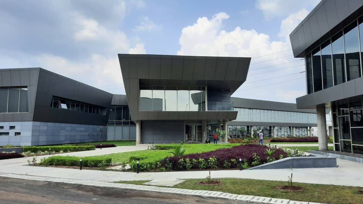 Modern grey metal and glass buildings with landscaped garden and overhanging roof.