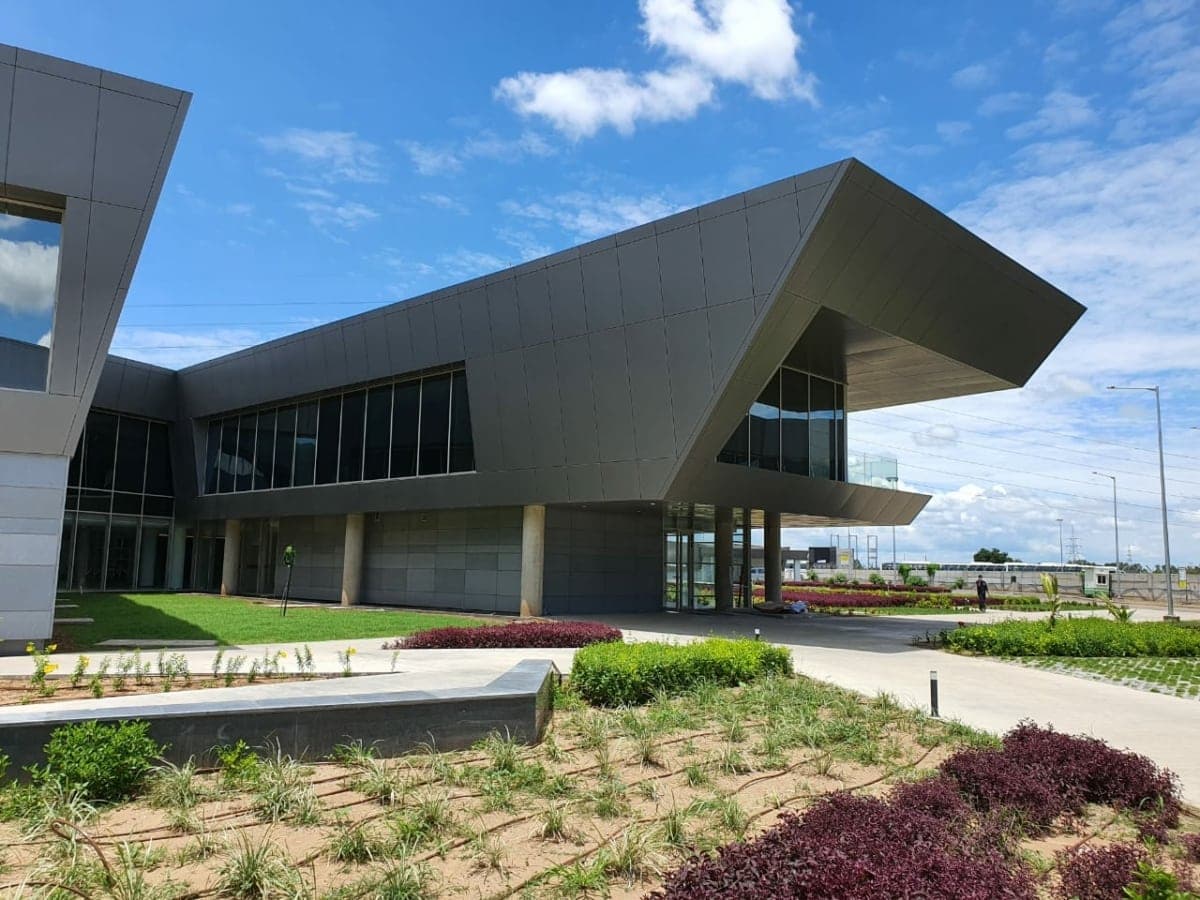 Modern architectural building with glass facade, overhang, and landscaped surroundings.