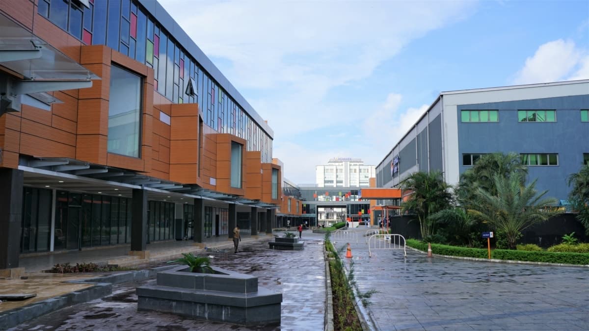 Modern business complex with retail shops, offices, and greenery on a bright day.