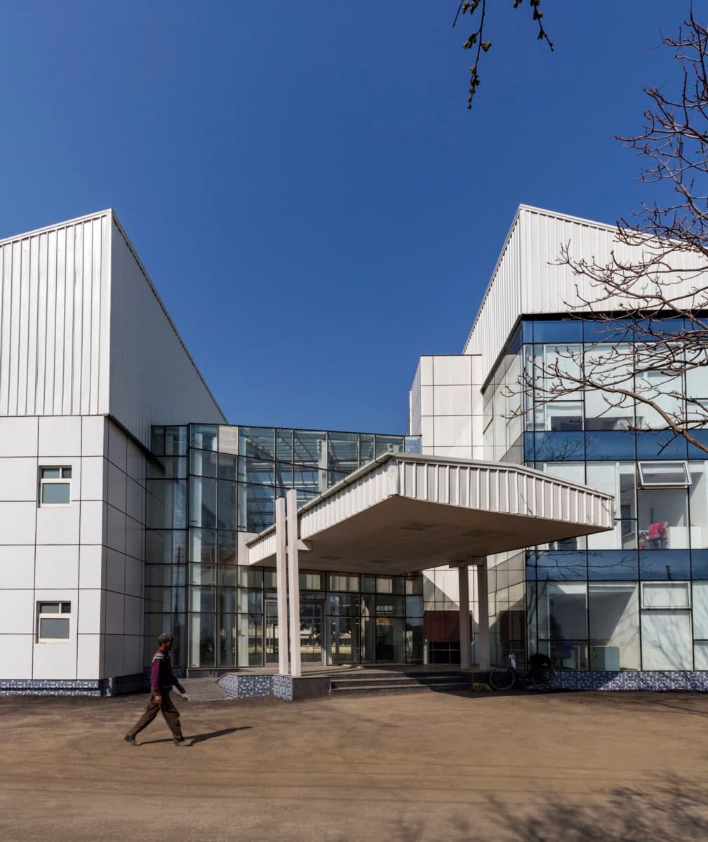 Modern Kashmir University Administration Building with glass facade under clear blue sky.