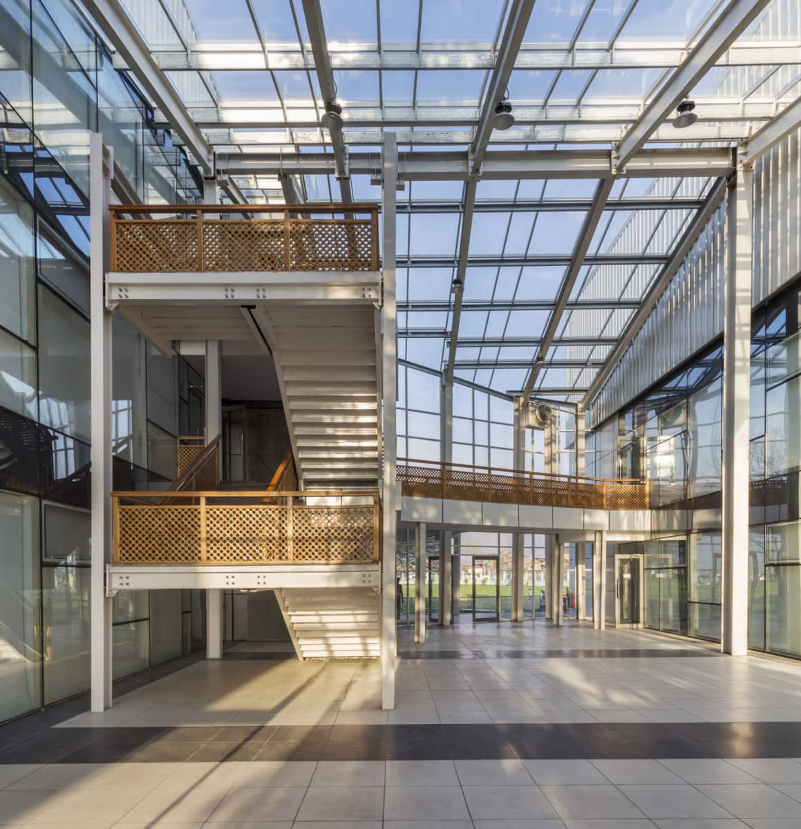 Modern glass atrium with white staircase and natural light at Kashmir University Administration Building.