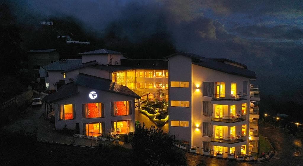Modern multi-story hotel illuminated against a dramatic evening sky.