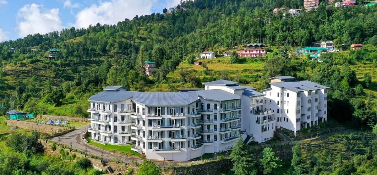 Modern multi-story hotel in lush mountainous landscape with scenic views and contemporary design.
