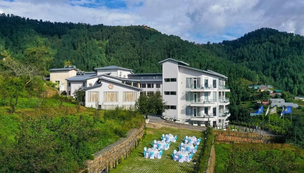Modern hotel amidst lush mountains with outdoor event setting. Peaceful retreat blending nature and comfort.