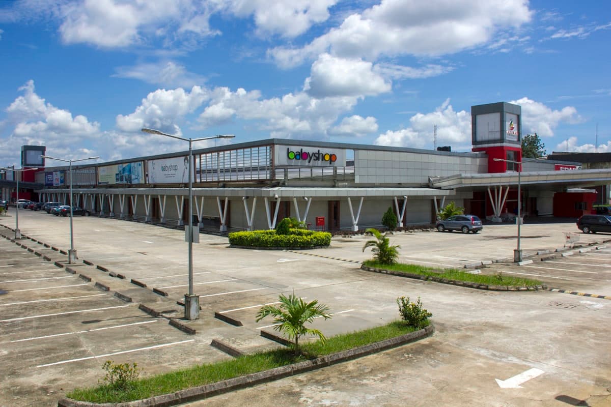 Modern Calabar shopping mall with sleek architecture, ample parking, and lush greenery.