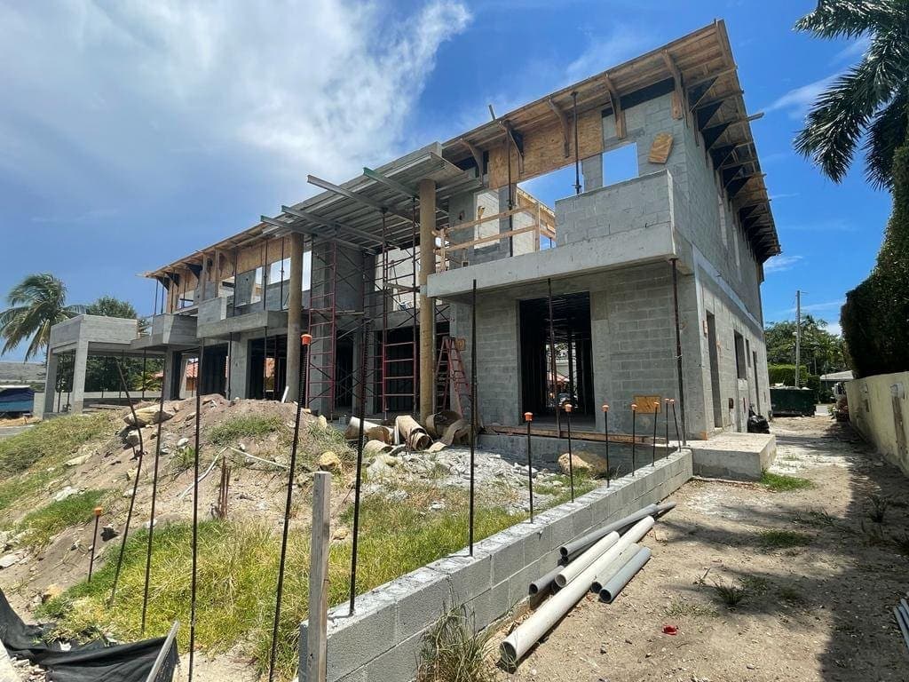 Unfinished concrete house structure with construction materials on site.