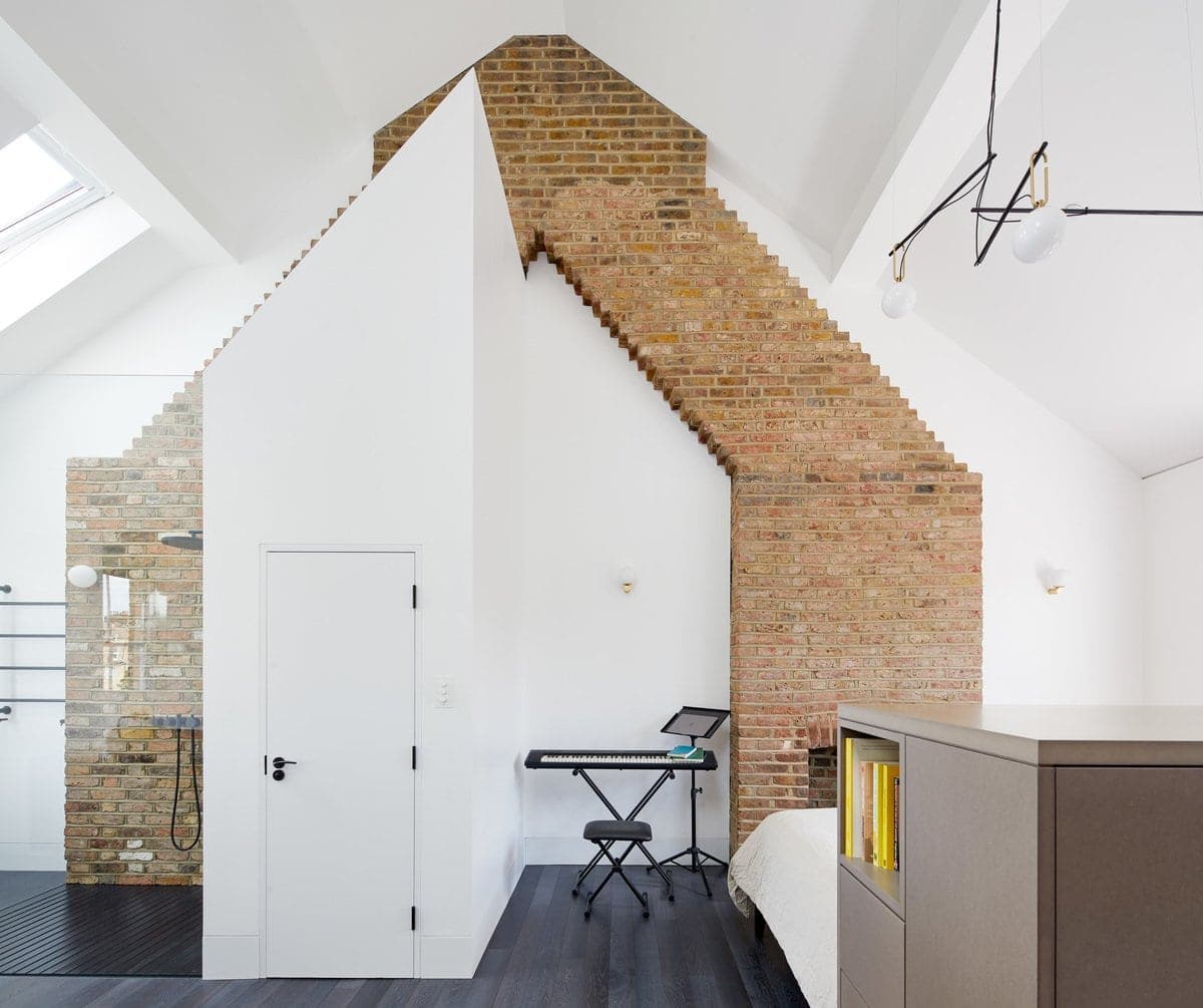 Modern loft bedroom with exposed brick wall, skylights, and contemporary decor.
